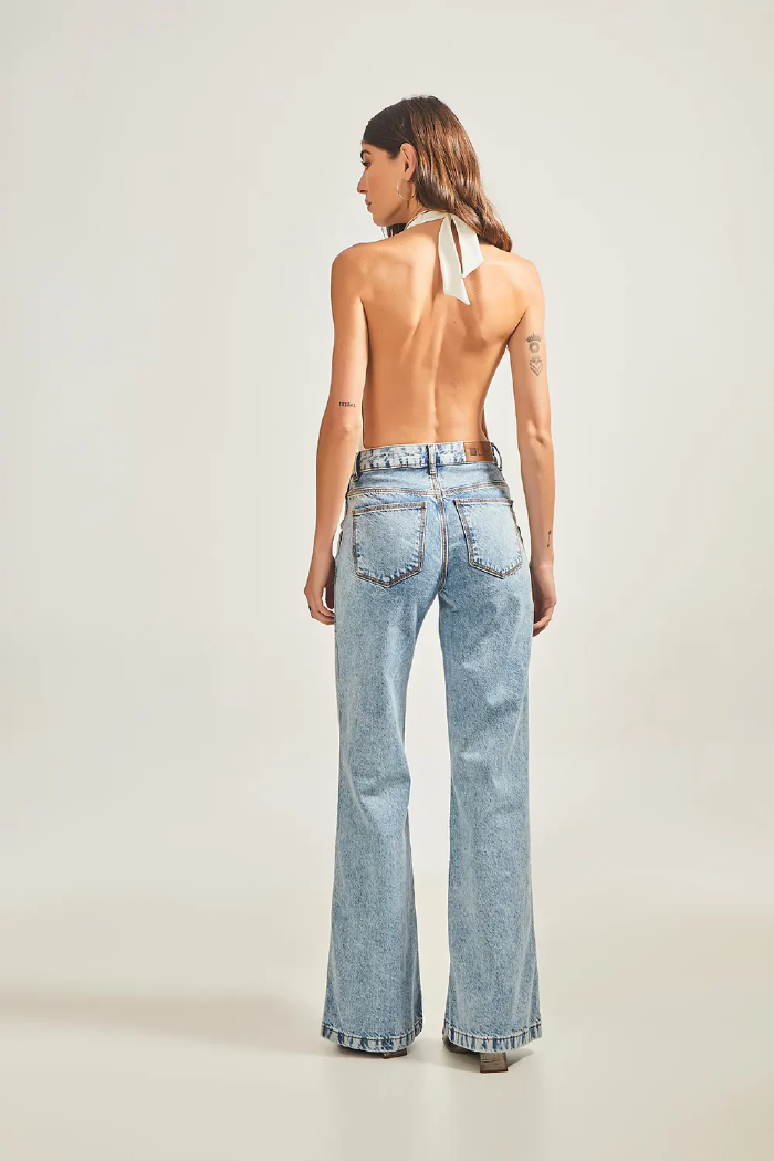 Modelo esta de costas vestindo Calça Jeans Wide Leg Bolso Sobreposto na cor Jeans Medio e body LINI Brazil.