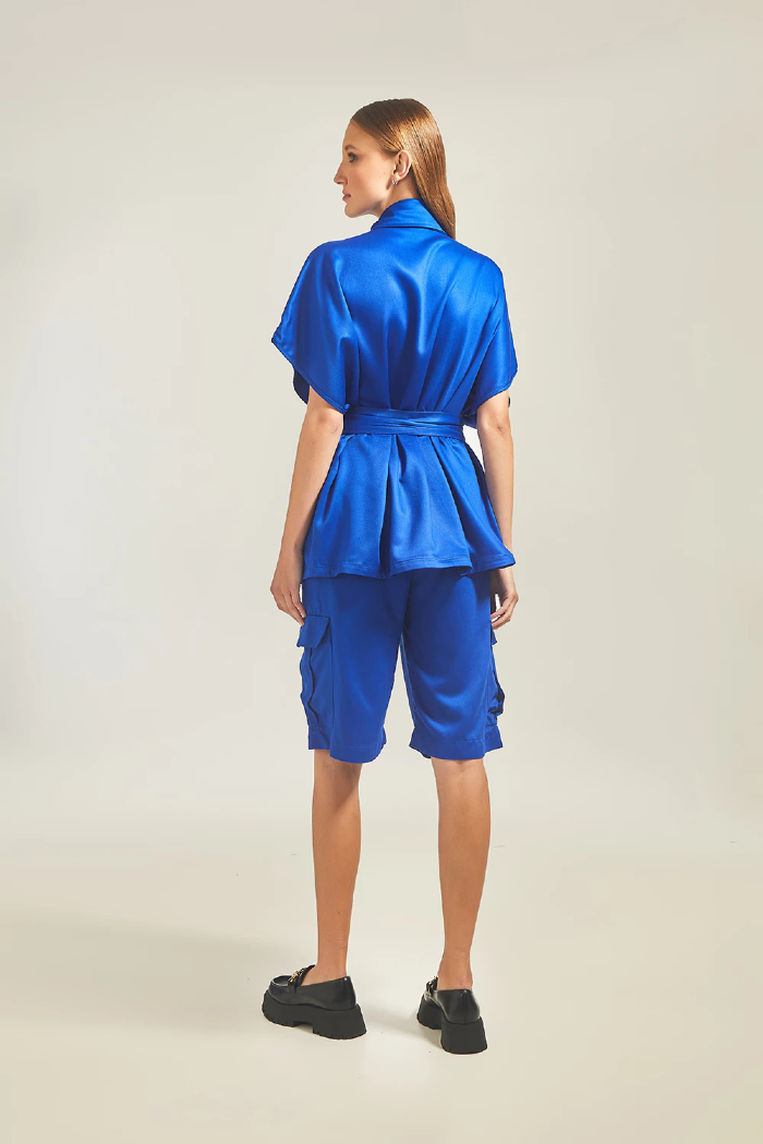 Modelo esta de costas vestindo Colete Cargo Lucy na cor azul medio e shorts LINI Brazil.