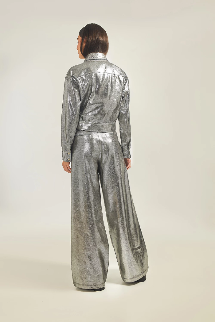 Modelo esta de costas vestindo Jaqueta Aline na cor prata e calça LINI Brazil.
