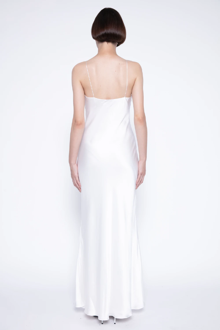 Modelo está de costas vestindo SLIP DRESS ENCANTARE na cor OFF_WHITE, LiNI . Vestido para o Reveillon