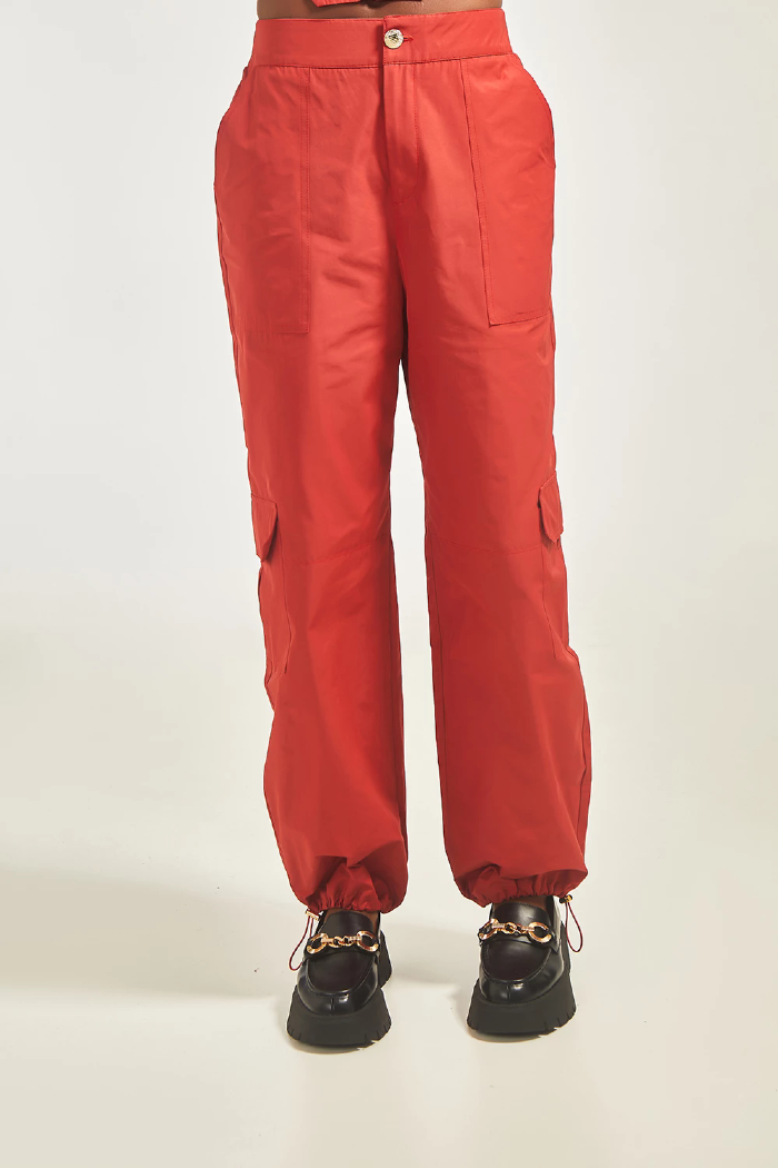 Modelo está vestindo Calça Cargo Ágata na cor vermelha, LiNI Brazil.